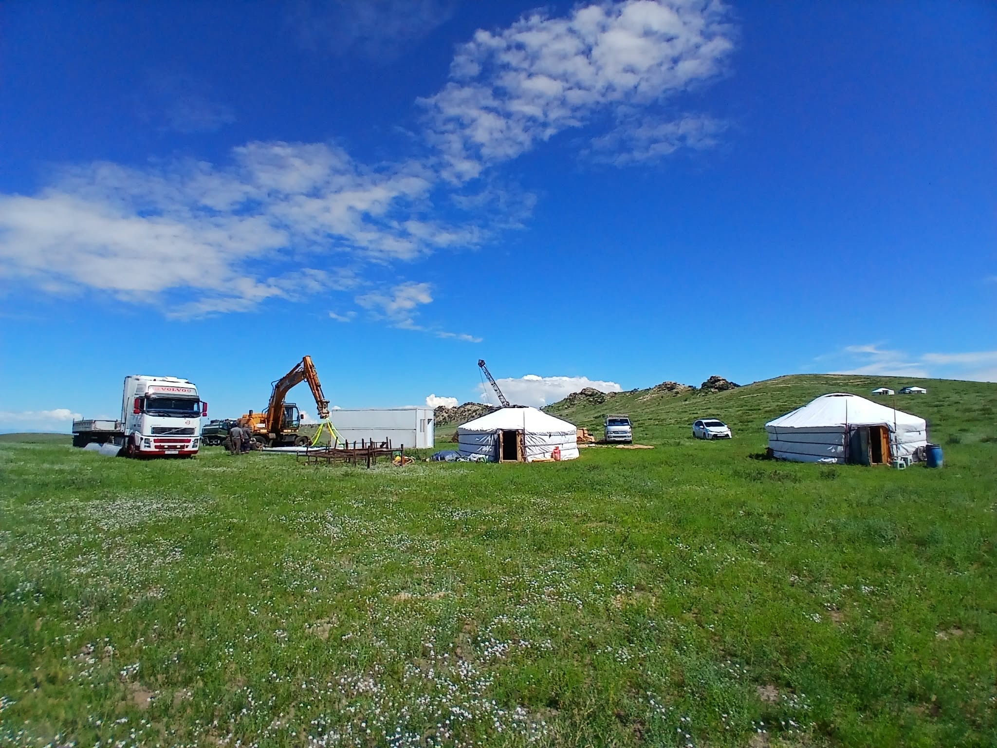 Exploration camp on the Mongolian steppe: trucks, excavator, container office and gers.