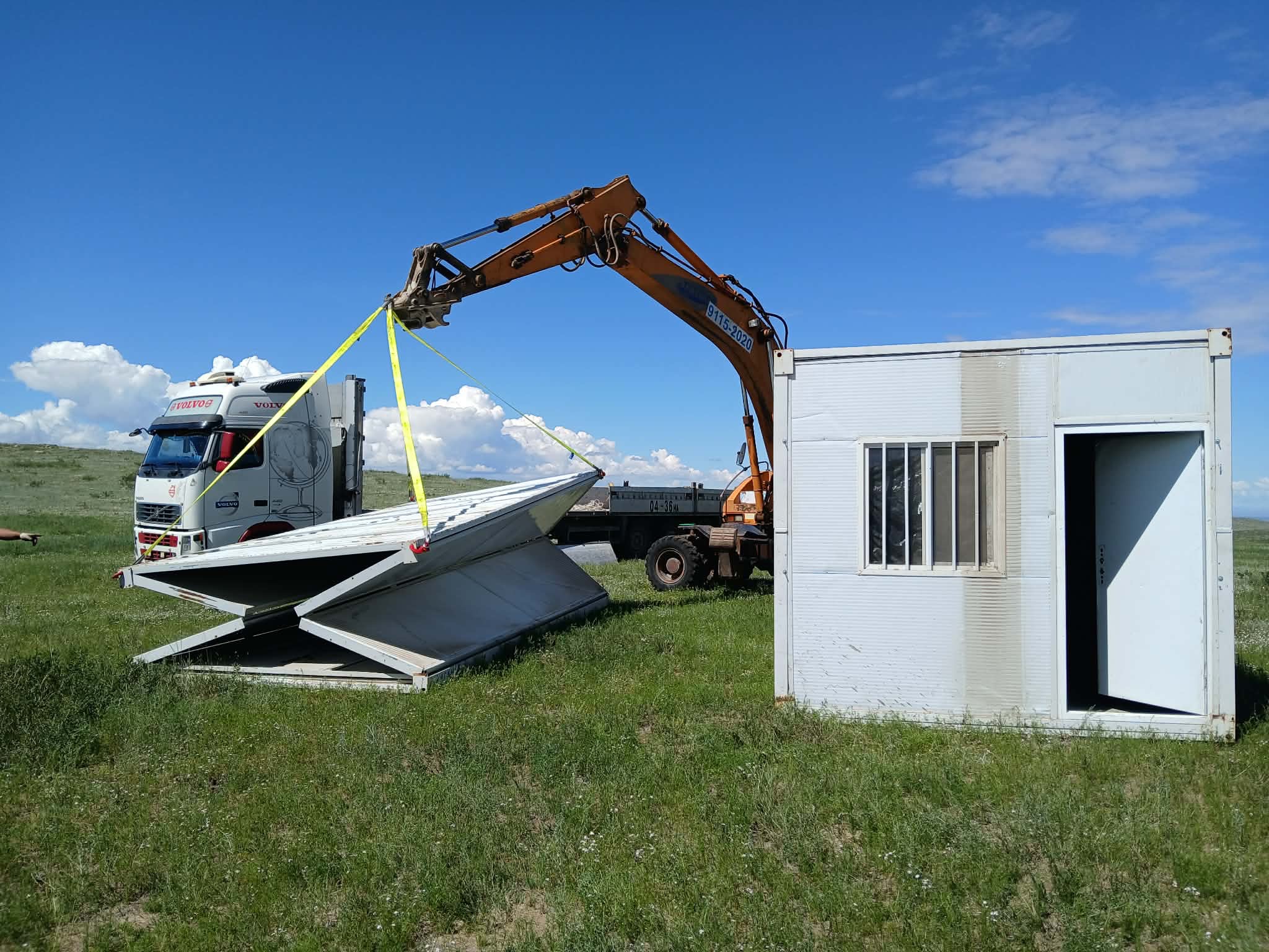 Excavator setting down the prefabricated field office.